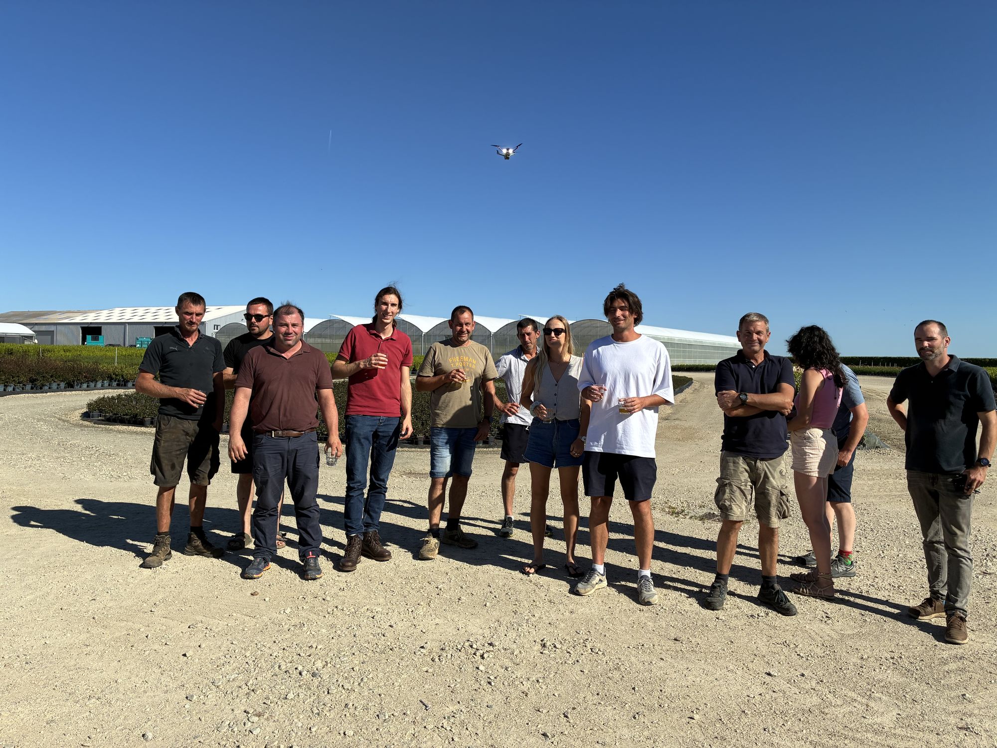 The Belver team in a field, with a drone in flight overhead